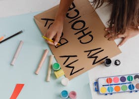 A woman crafting an empowerment protest poster with art supplies from a high angle view.